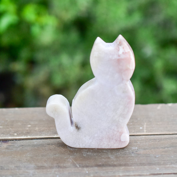 Whyte Quartz Grade A Pink Amethyst Sitting Cat on wood table with greenery outdoors